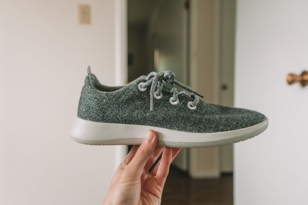 Holding up a grey and white Allbirds Wool Runner to see the side profile.
