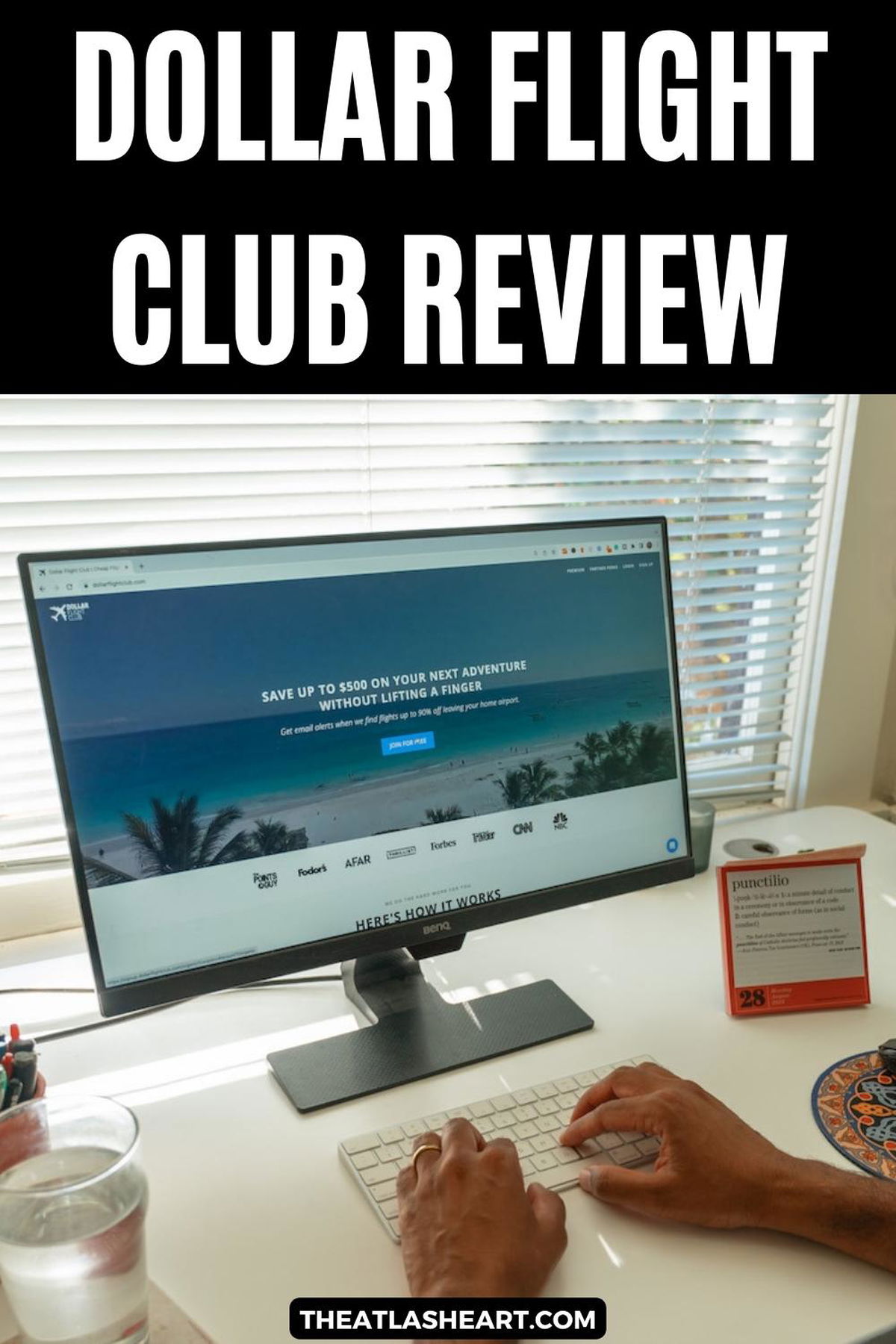 A pair of hands typing on a keyboard on a computer desk in front of a desktop monitor displaying the Dollar Flight Club website homepage, with the text overlay, "Dollar Flight Club Review."