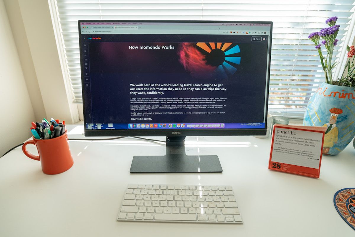 A view of a white desk with a computer monitor sitting on it, displaying the Momondo website 'About' page.