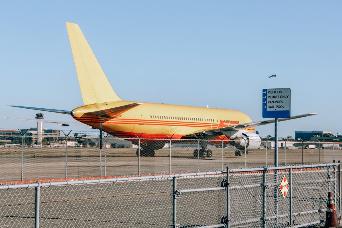 A yellow and red plane on the runway at Long Beach Airport (LGB) with a clear blue sky behind it.