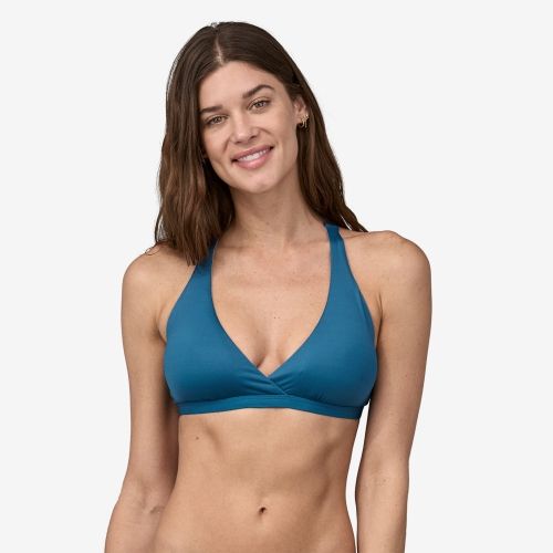 Product photo for the Patagonia Bottom Turn Racerback Bikini Top in blue, modeled by a smiling brunette. 