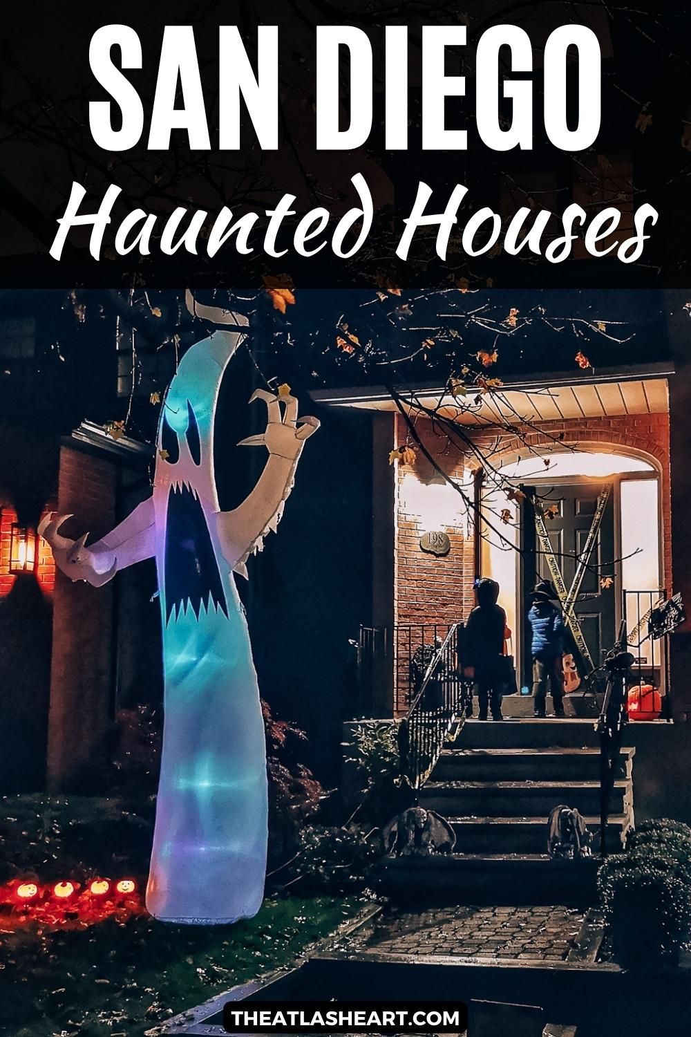 Two children knocking on the door of a house decorated heavily for Halloween at night time, with the text overlay, "San Diego Haunted Houses."