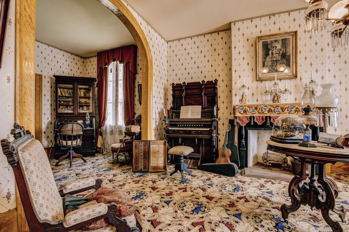 An interior view of the Thomas Whaley House, a sumptuously-decorated Victorian parlor with beige, patterned wallpaper and carpet.