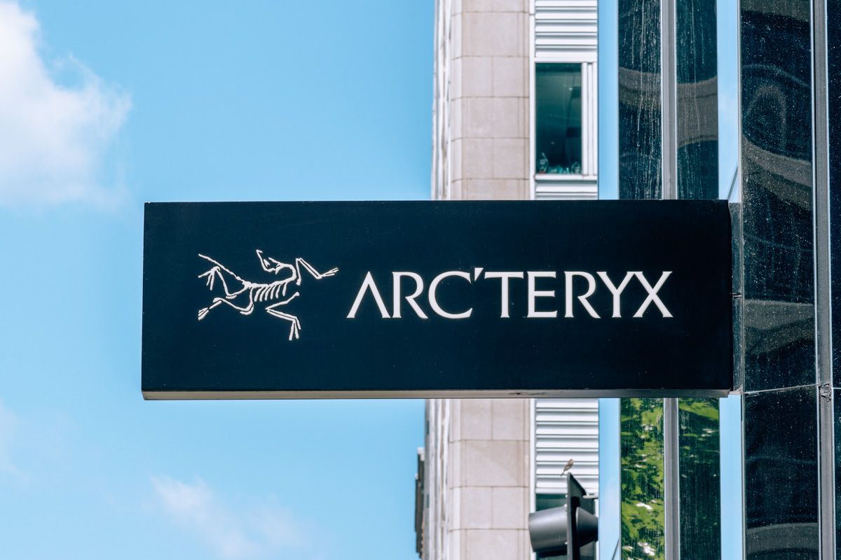 A black sign with white lettering that reads, "Arc'teryx" sticking out from the side of an office building.