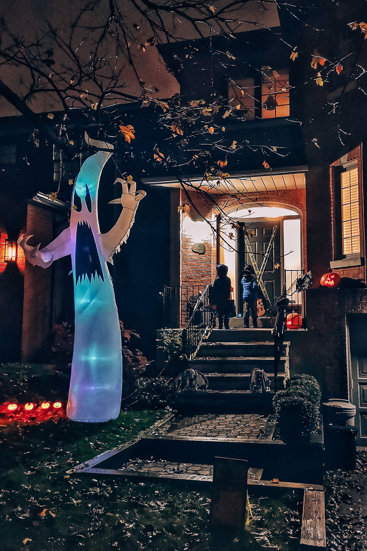 San Diego Haunted Houses-- Two children knocking on the door of a house decorated heavily for Halloween at night time.