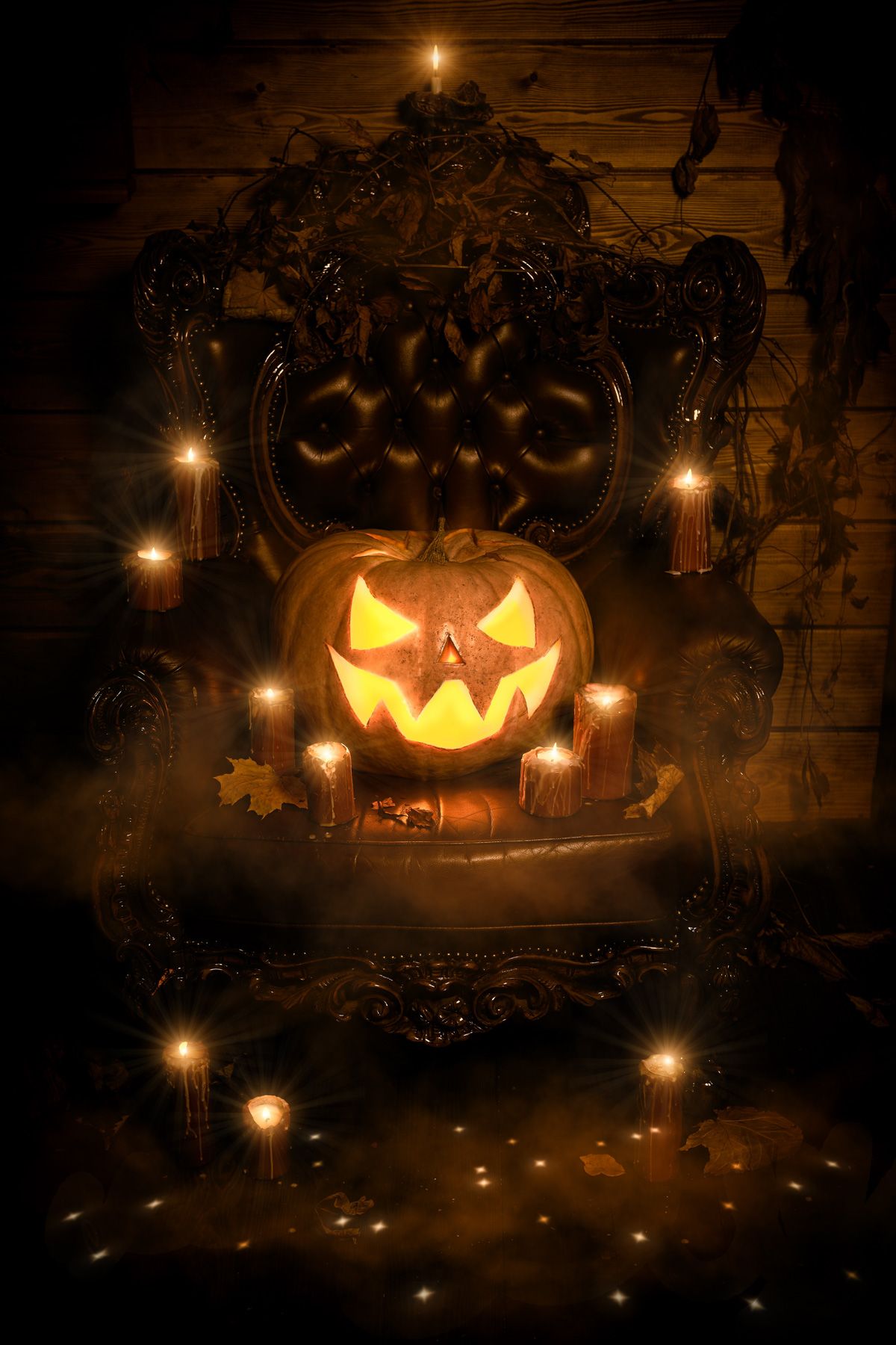 Los Angeles Haunted Houses: A glowing jack-o-lantern in dim light sits on an ornate leather armchair, surrounded by candles and fall leaves.