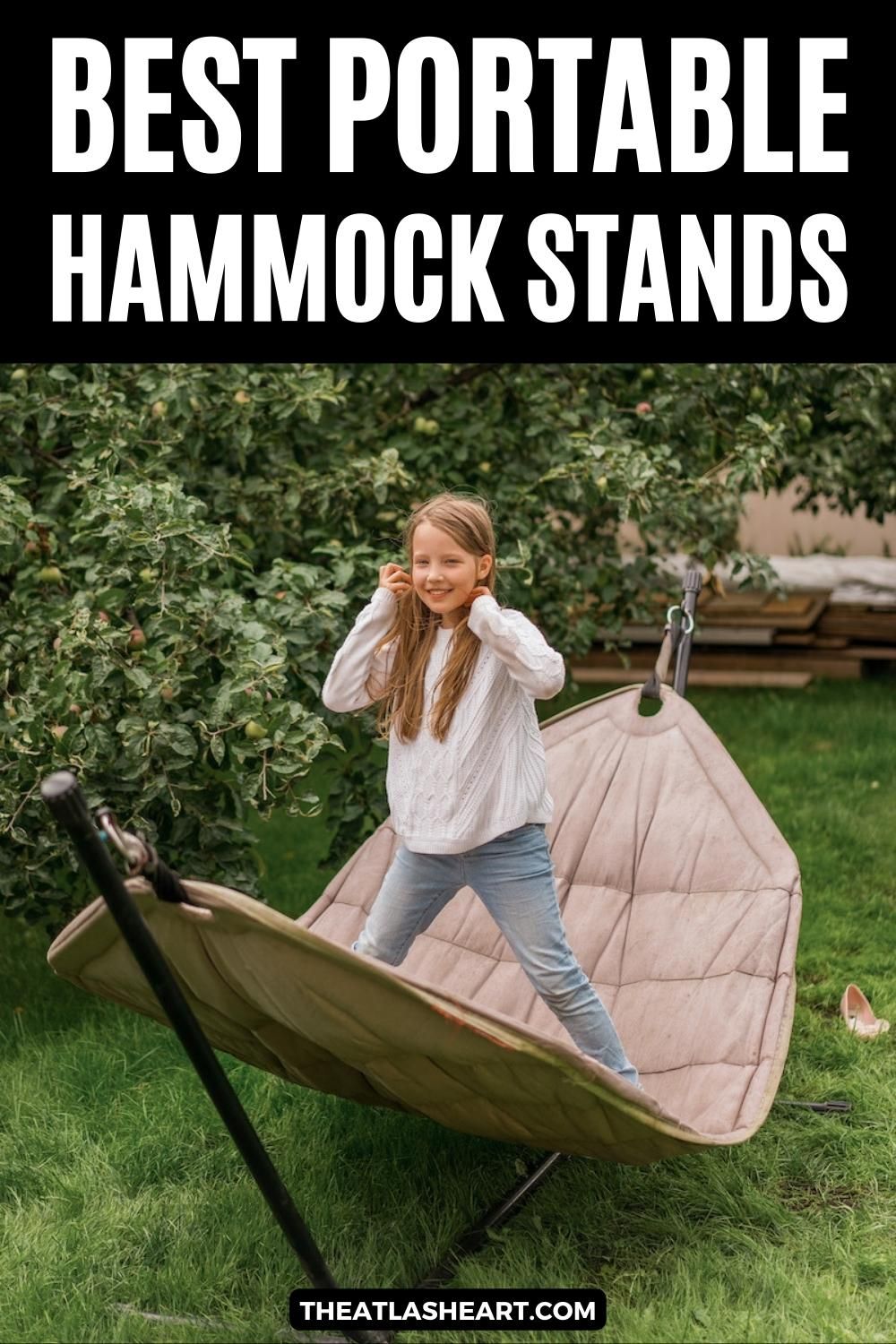 A young blonde girl wearing jeans and a white sweater stands on a grey hammock supported by a stand next to an apple tree in a backyard setting, with the text overlay, "Best Portable Hammock Stands."
