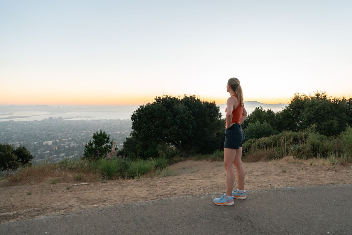 Mimi with her back to the camera, looking out at the Berkeley skyline after sunset, when the horizon is still orange.