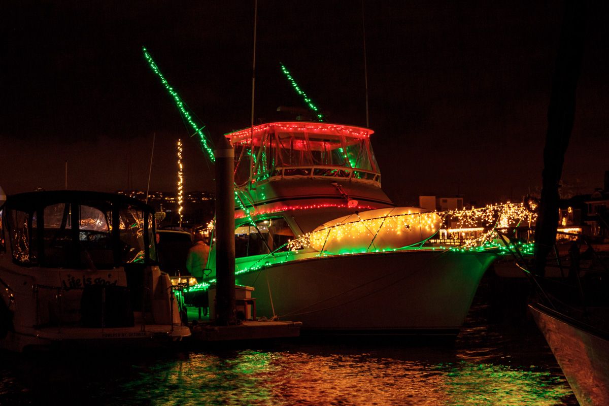 Annual Newport Beach Christmas Boat Parade & Ring of Lights
A dark yacht docked and decorated in green, red, and white lights, which reflect off of the water.