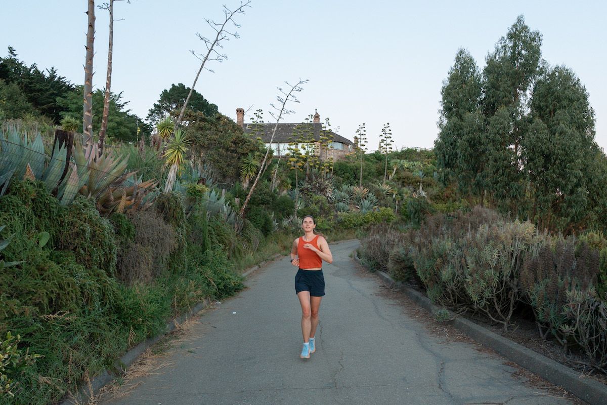 Mimi jogging in her Hoka sneakers on a quiet road lined with cacti, juniper, and palms.