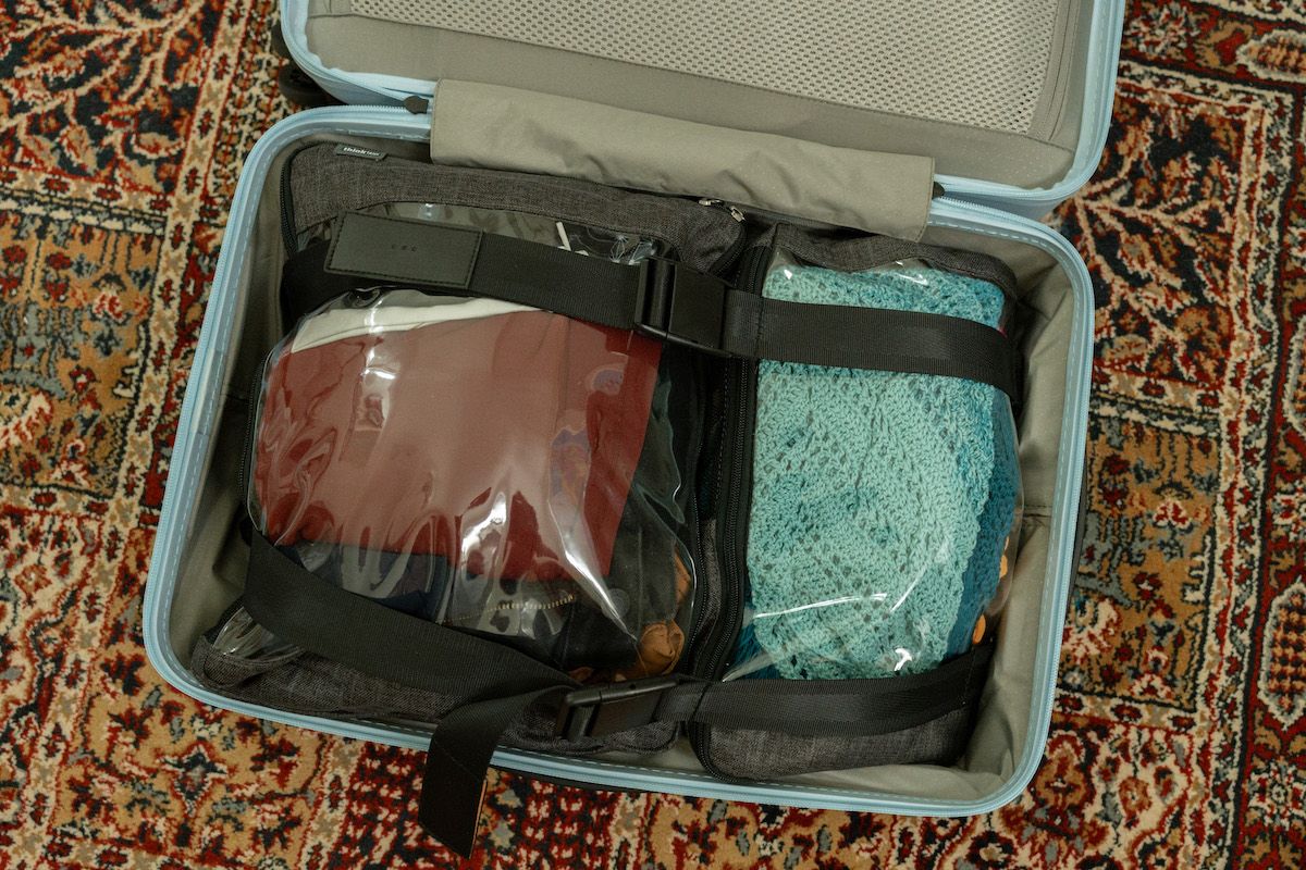 And open suitcase sitting on a red oriental rug neatly packed with packing cubes.