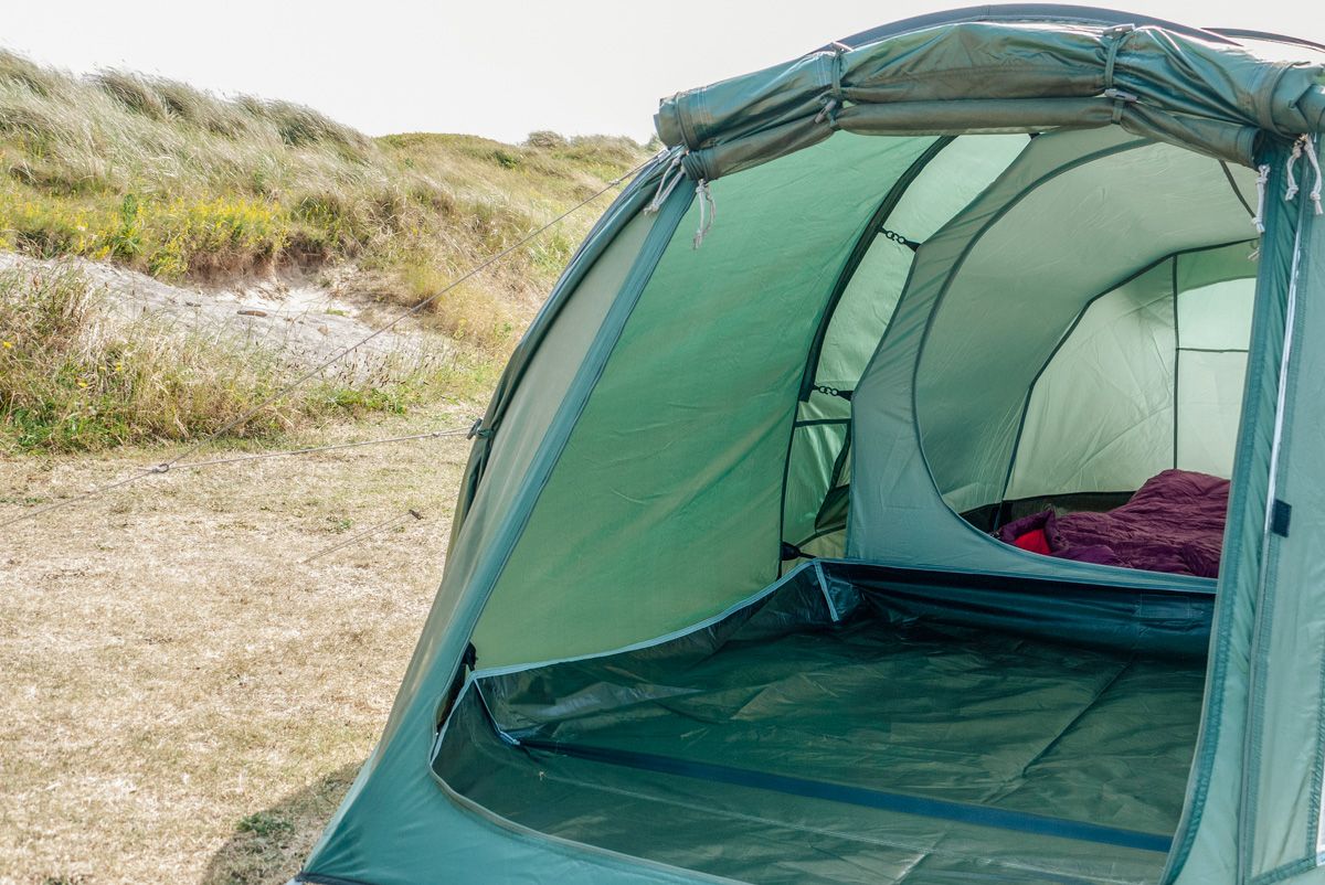 FAQs About Tall Tents
Looking into a green tent with a large vestibule and sleeping space in the foreground and a dry grassy hill in the background.