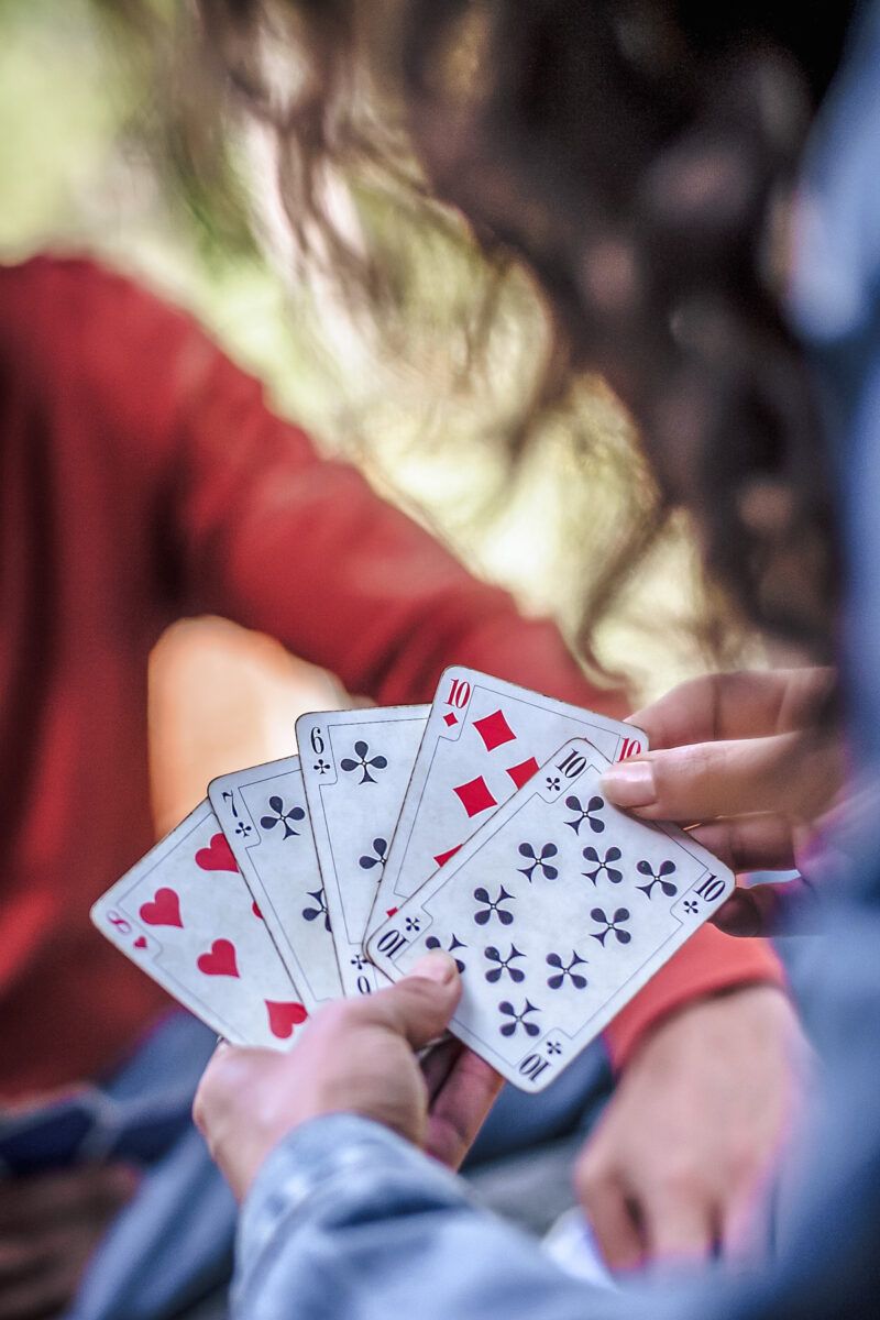 Camping Games for Adults
A close up of a woman holding five cards in her hand and choosing the 10 of diamonds.