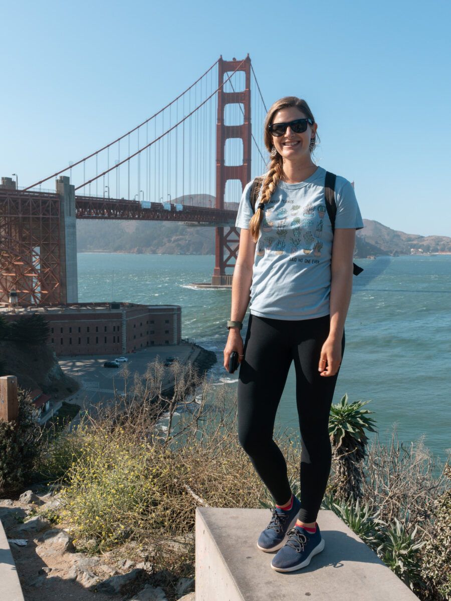 A photo of Mimi standing in front of the Golden Gate Bridge in San Francisco on a clear day. 