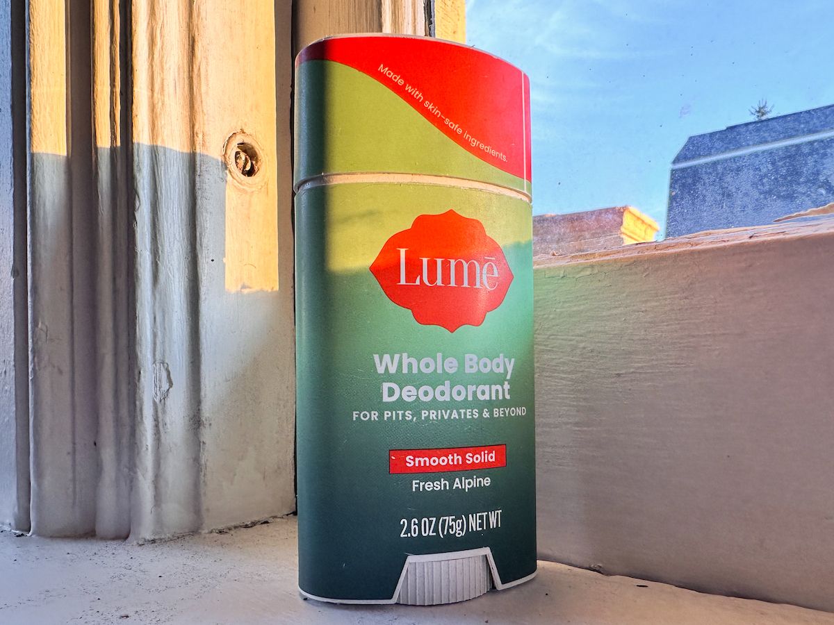A stick of Fresh Alpine Lume deodorant sitting on a windowsill, with a blue sky visible through the pane.