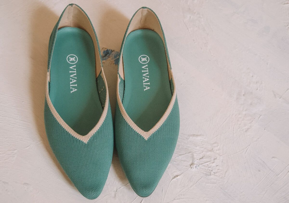 A pair of teal Vivaia flats sitting on a white background.