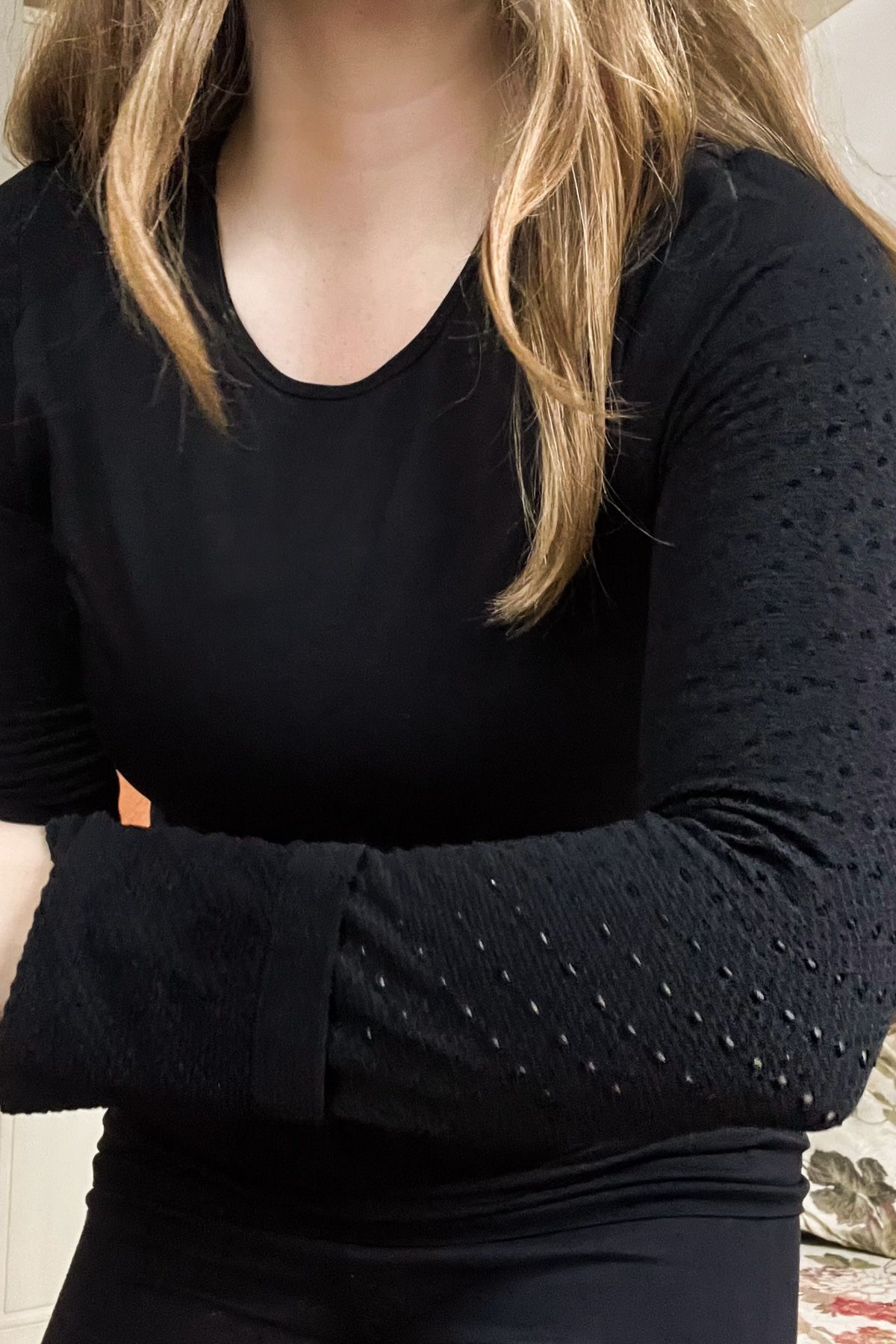 Close-up of a young woman's arm in a long-sleeved black top and black leggings.