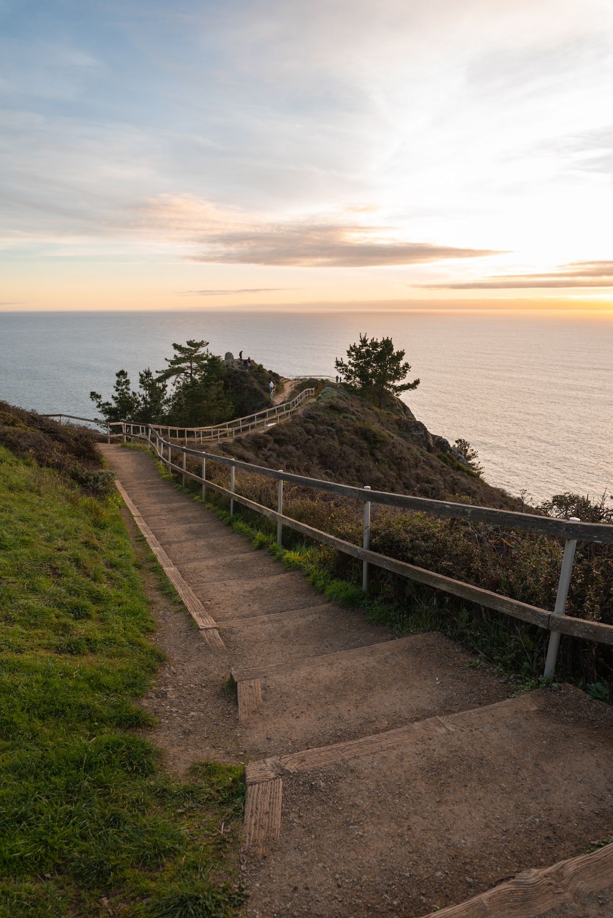 A view looking down some dirt stairs leading towards the Muir Beach Overlook, bathed in the golden light of sunset.