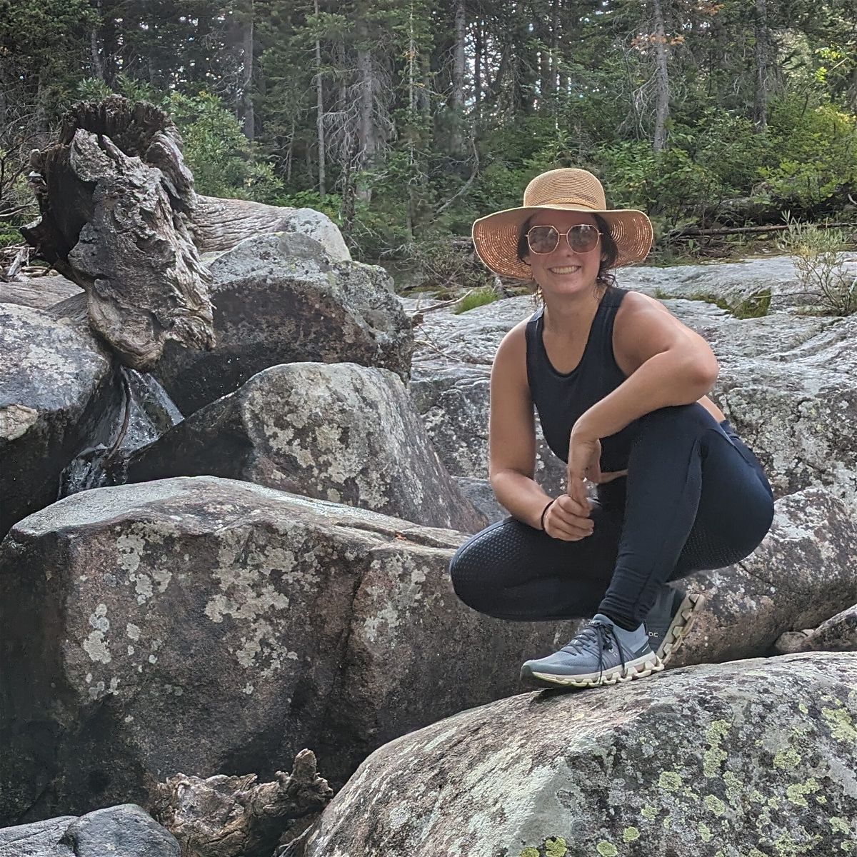 Jodelle posing in a sun hat on boulders during a hike.